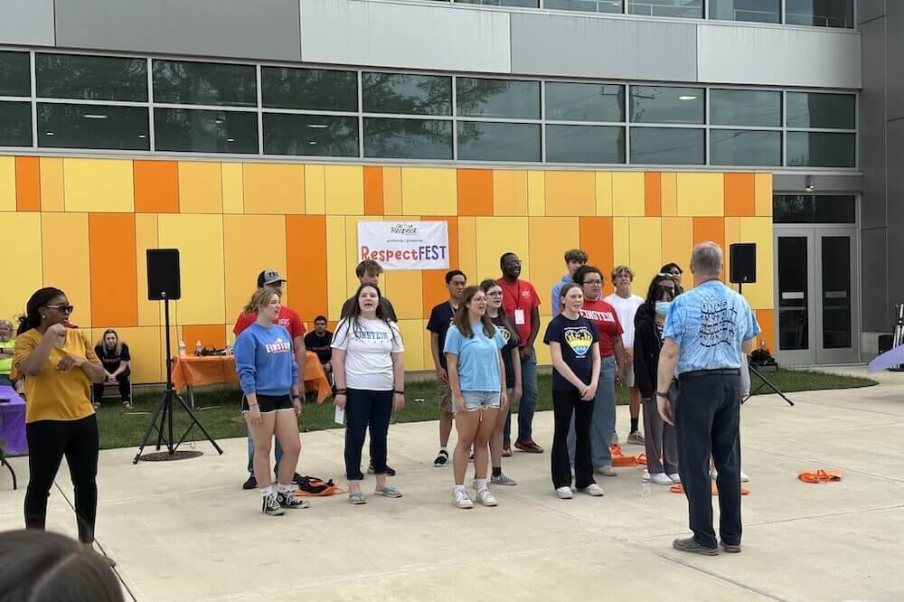 A group of 15 students from Albert Einsteign High School singing outside